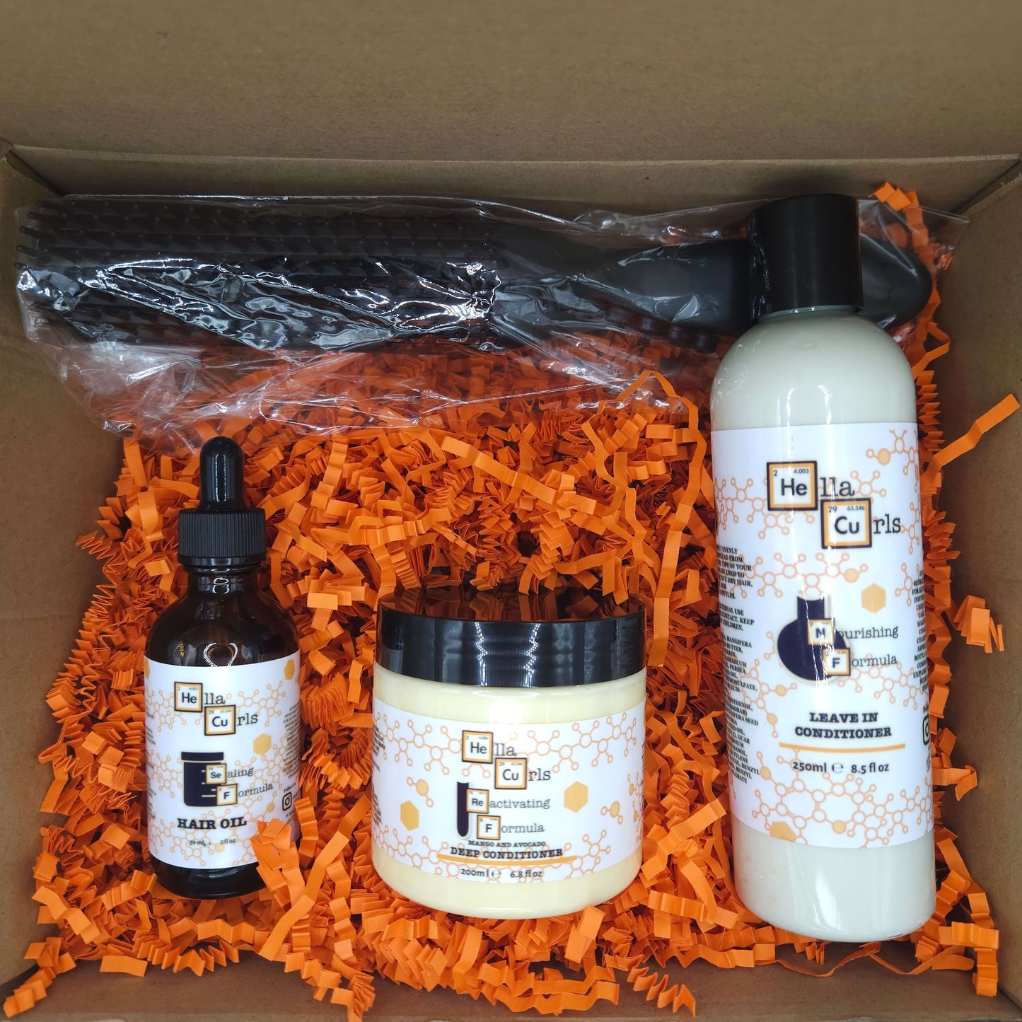 Set of hair care products including a bottle, jar, and other items on orange shredded paper.