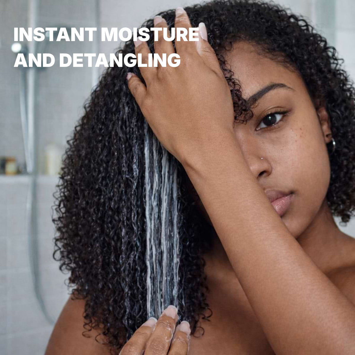 Woman with curly hair in a bathroom setting with text 'Instant Moisture and Detangling'.
