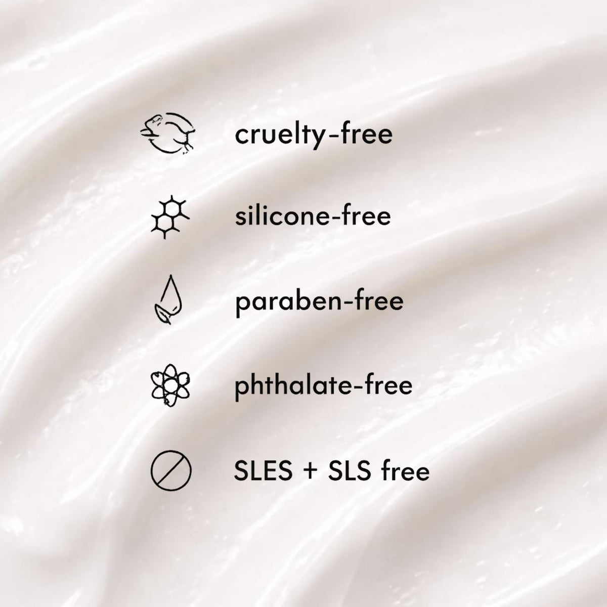 Close-up of a smooth, white cream texture with 'cruelty-free', 'silicone-free', 'paraben-free', 'phthalate-free', and 'SLES + SLS free' labels.