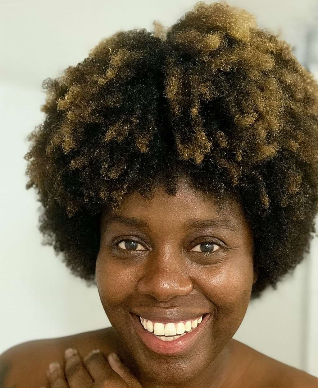 Woman with an afro hairstyle smiling against a white background