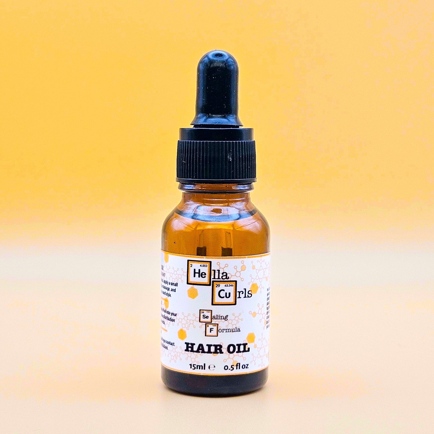 Bottle of Hella Curls Sealing Formula hair oil with a dropper on a gradient yellow background